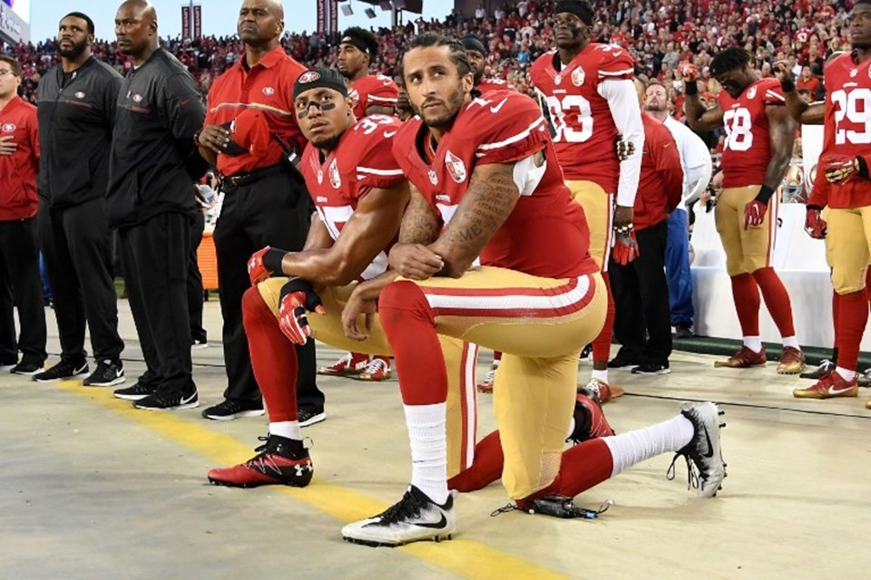 Colin Kaepernick ve Eric Reid milli marş sırasında dizlerinin üstüne çökerek protesto ediyor.