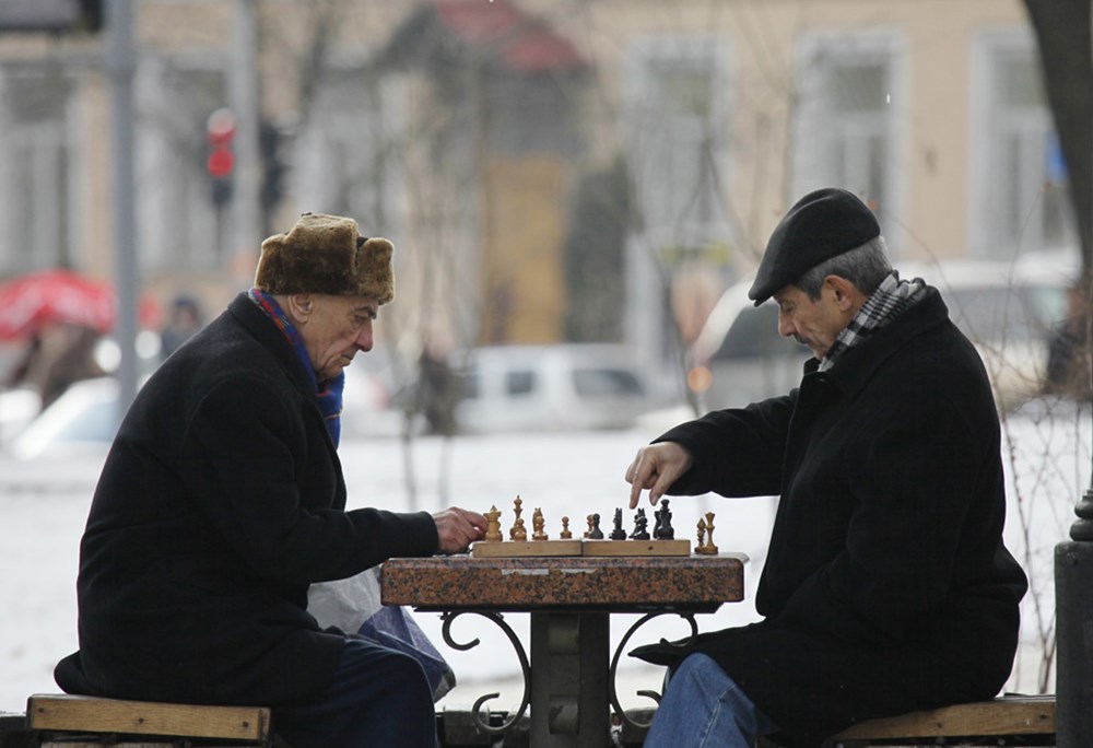 Мужчины играют в шахматы. Мужчина играет в шахматы. Шахматисты на лавочке. Шахматисты в парке. Человек за шахматами.