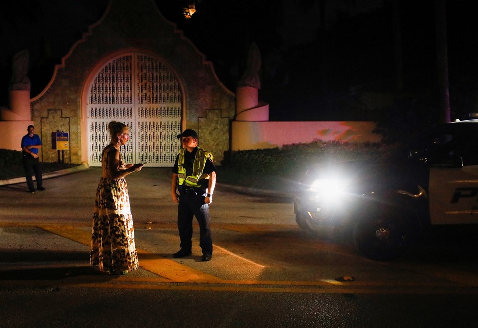 Bir polis memuru, Trump'ın Mar-a-Lago evinin önünde bir kadınla konuşuyor.