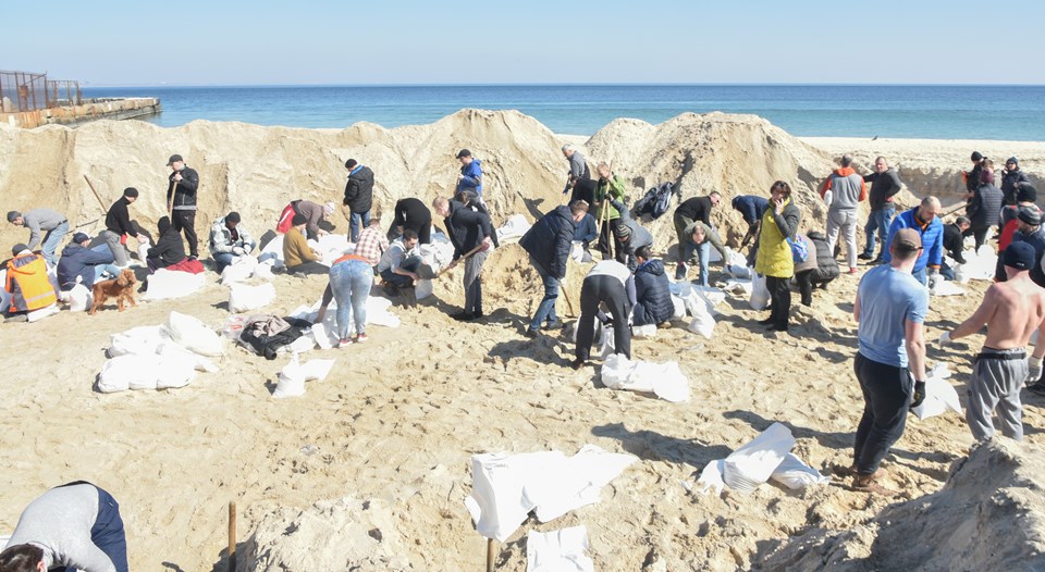 Rusya saldırısı altındaki Ukrayna'nın Odessa kentindeki sahilde bulunan yaklaşık 100 gönüllü, çuvallara kum doldurarak yol barikatlarına destek veriyor.