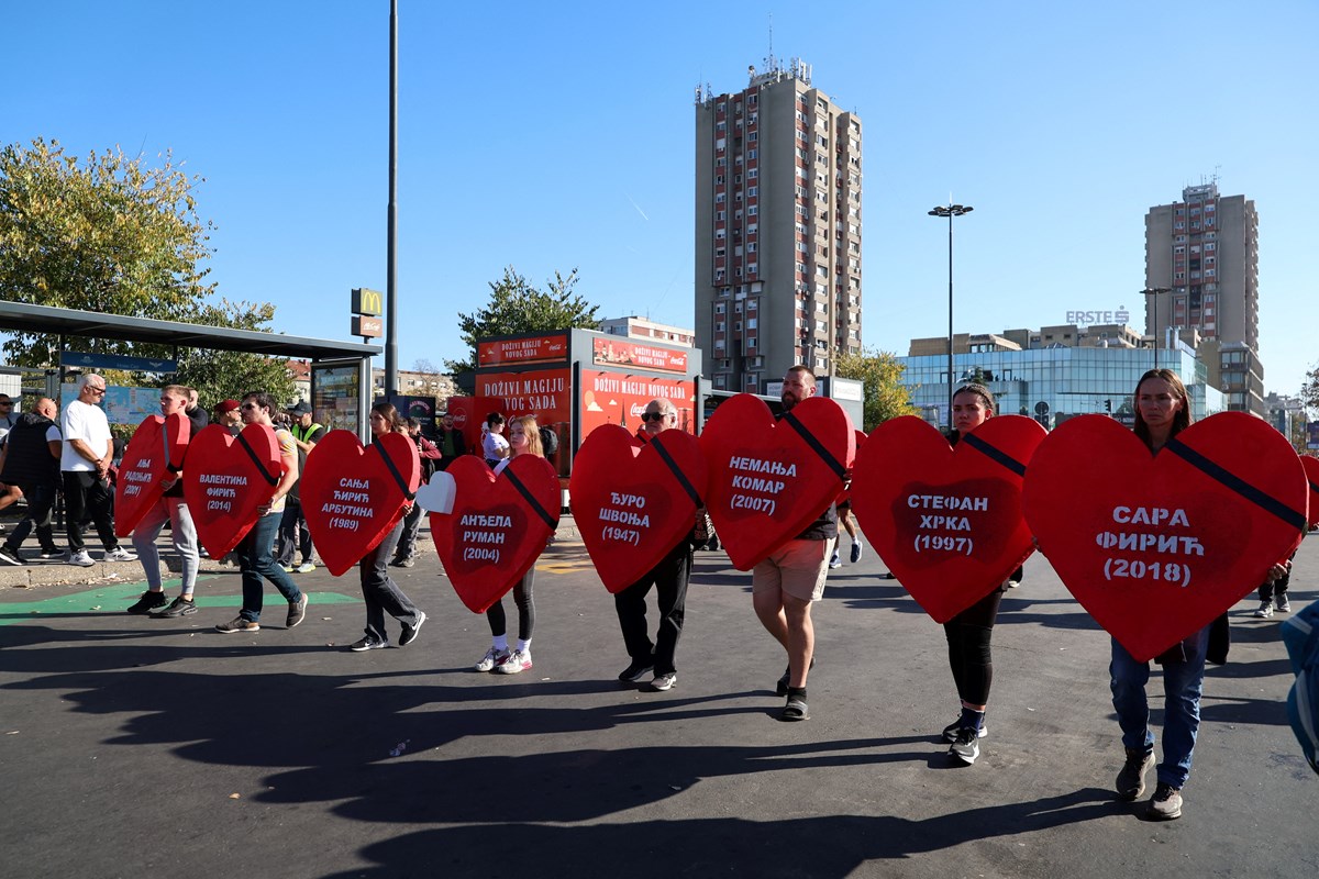 Katılımcılar üzerlerine kurbanların isimlerinin yazılı olduğu kalpler tutuyorlar.