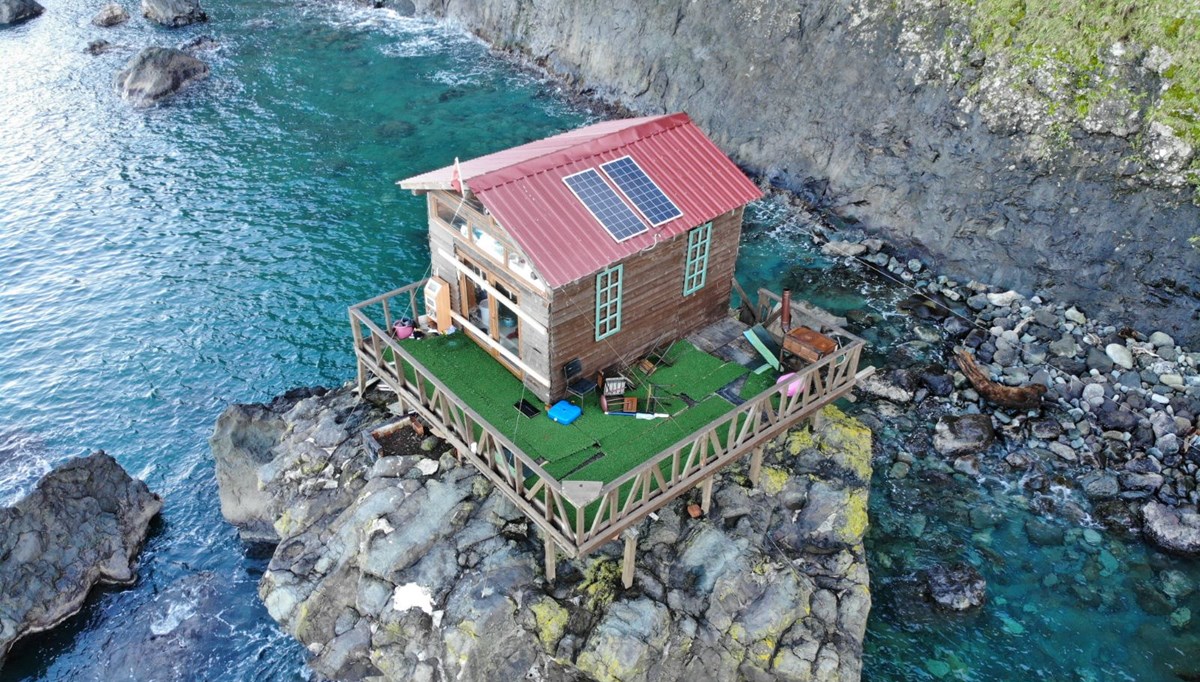 Deniz kıyısındaki kayanın üzerine yapılan baraka dikkat çekiyor