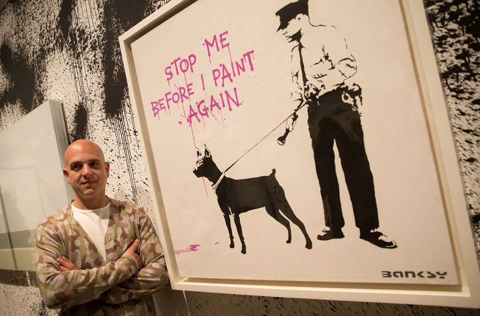 Steve Lazarides (47) "yeniden boyamadan önce beni durdur" yazılı bir Banksy çalışması önünde poz veriyor.