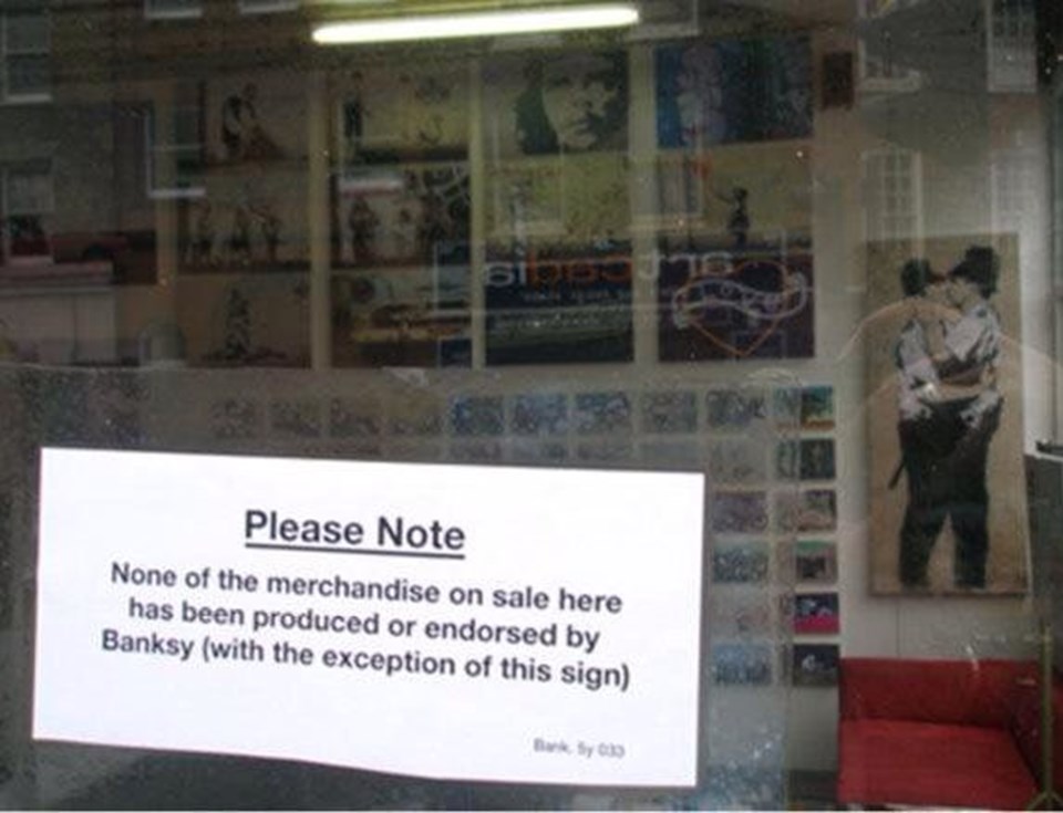 Banksy'nin işlerinin satıldığı bir mağazanın camında asılı uyarı: Burada satılan hiçbir ürün Banksy tarafından üretilmemiş ve üretimi teşvik edilmemiştir. Bu uyarı yazısı hariç.