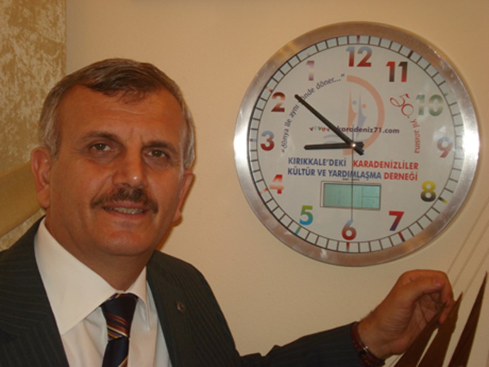 Prof. Dr. Cevdet Erdöl, saatin önünde poz verdi.